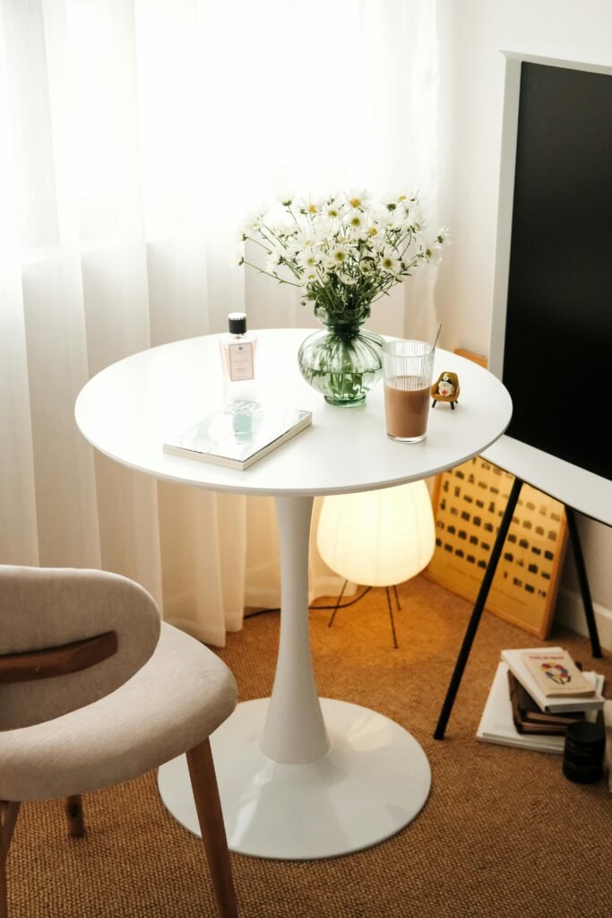 oil-1 A serene and elegantly arranged table setup with daisies, books, and decor in a stylish room.